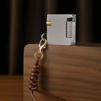 A Thorens Mini Cube lighter with a silver mesh texture and brass ignition wheel, standing upright on a wooden block with a leather lanyard.