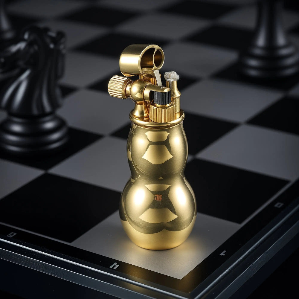 A vertical shot of a polished brass Mini Gourd lighter with its mechanical cap open, standing on a chessboard to showcase its elegant curves and ignition wick.