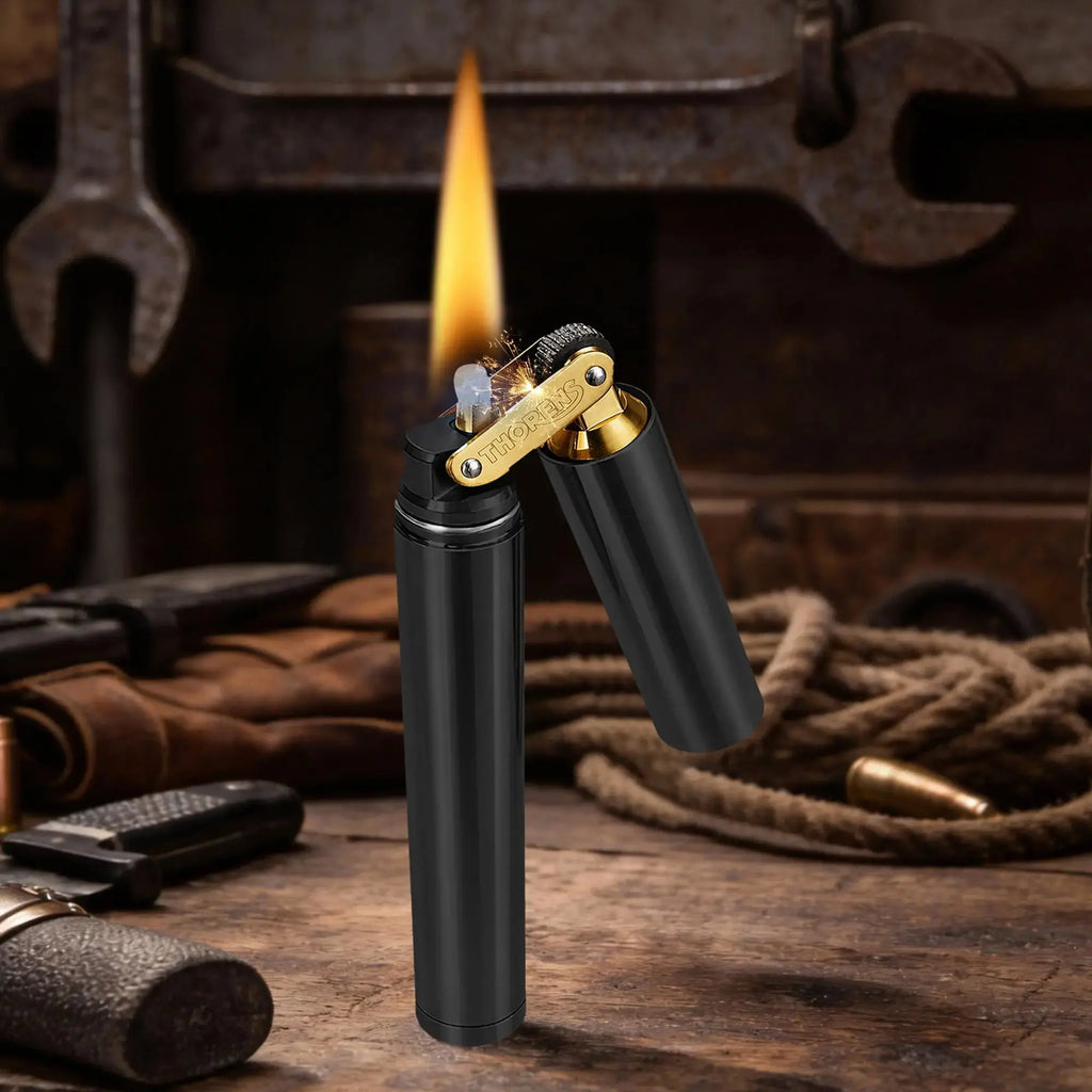 An ignited Thorens Nunchaku lighter in a matte black finish standing on a rustic workbench. The shot captures a steady flame and sparks flying from the brass mechanical wheel against a dark, industrial workshop background.