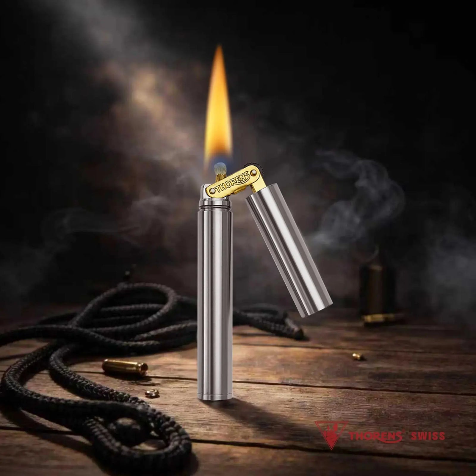 A Thorens Nunchaku lighter in silver chrome standing ignited on a rustic wooden surface, featuring a steady yellow flame and atmospheric smoke against a dark workshop backdrop.