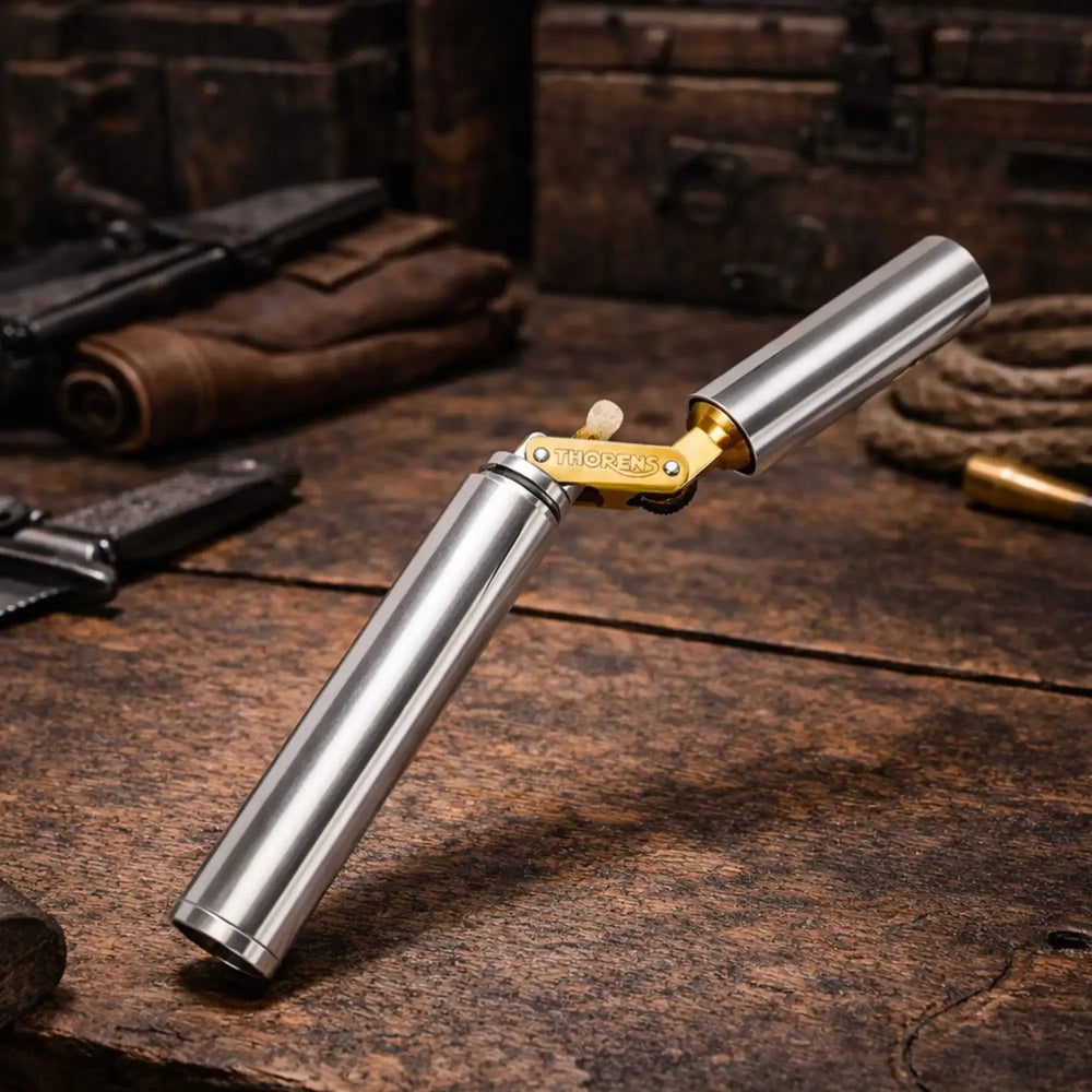 A Thorens Nunchaku lighter in silver chrome resting on a rustic wooden workbench, showcasing its unique cylindrical "trench style" design and premium mechanical brass hinge.
