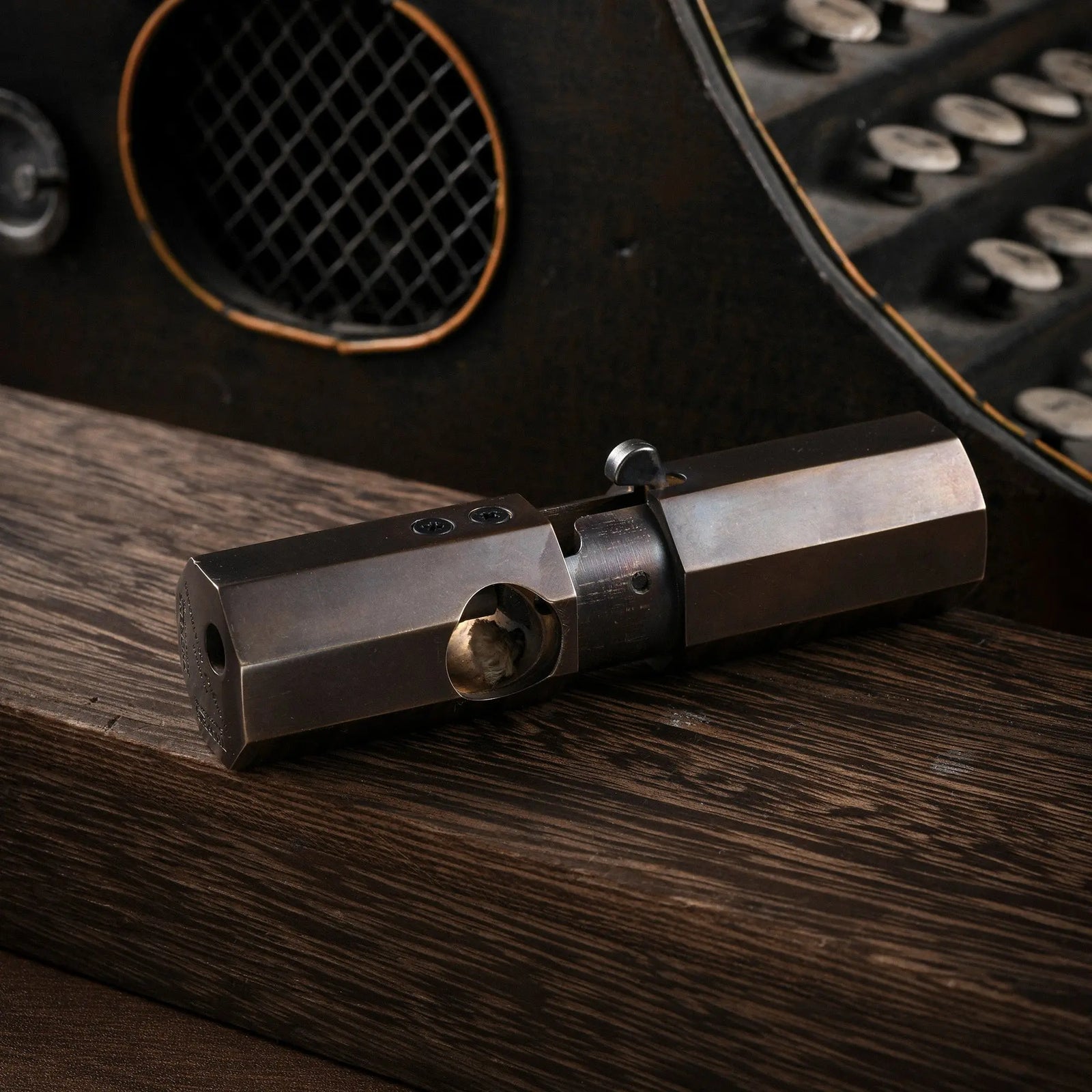 A horizontal profile of the Octagon Trigger lighter resting on wood, featuring a smooth glossy finish on its antiqued brass octagonal body.