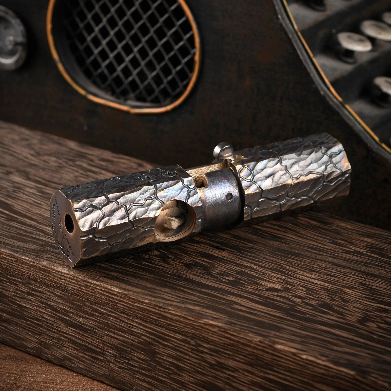 Horizontal view of an Octagon Trigger lighter resting on wood, highlighting the hand-carved earth fissure texture and aged brass craftsmanship.