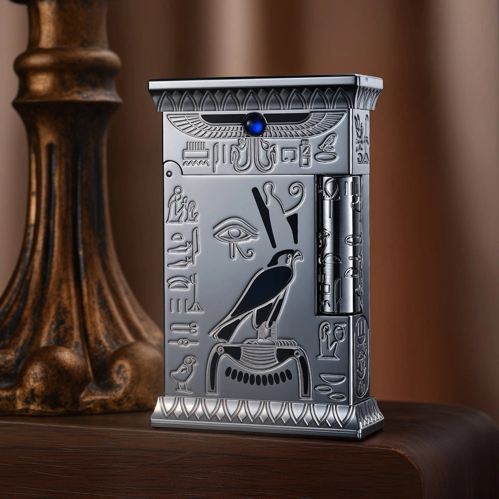 Standing Pharaoh's Light Silver lighter with a matte chrome finish, featuring deep-etched Egyptian motifs, a Falcon of Horus, and a blue gemstone.