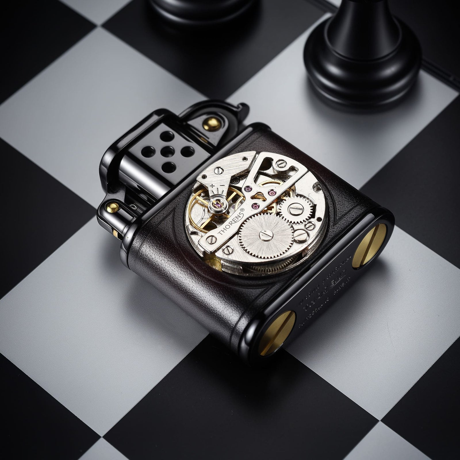 Angled close-up view of the THORENS handmade cowhide lighter with inlaid mechanical movement in red and black color, highlighting the front movement window and bottom screws.