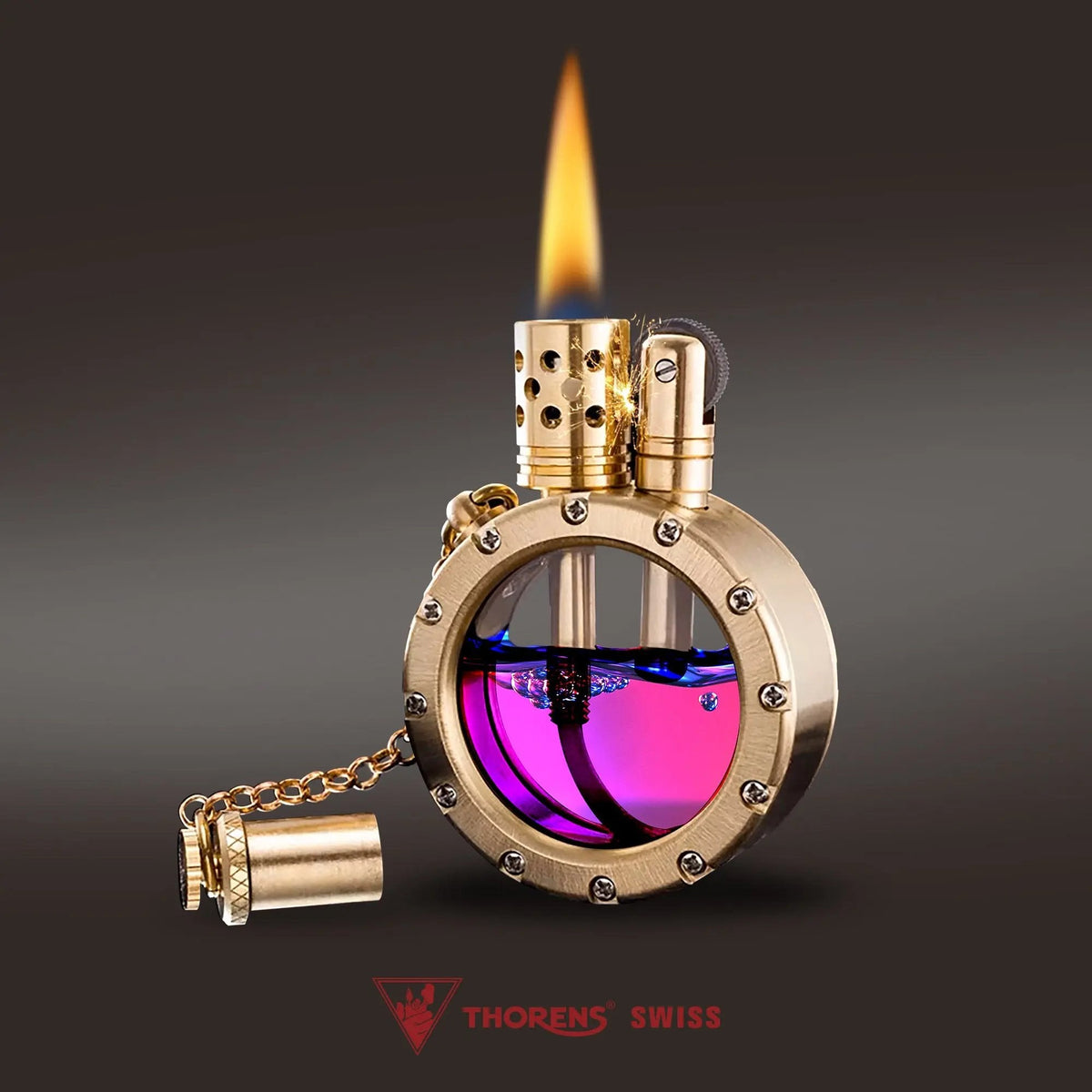 An ignited brass Round Pocket Watch Lighter displaying a steady yellow flame, featuring a transparent tank filled with purple and blue fuel.