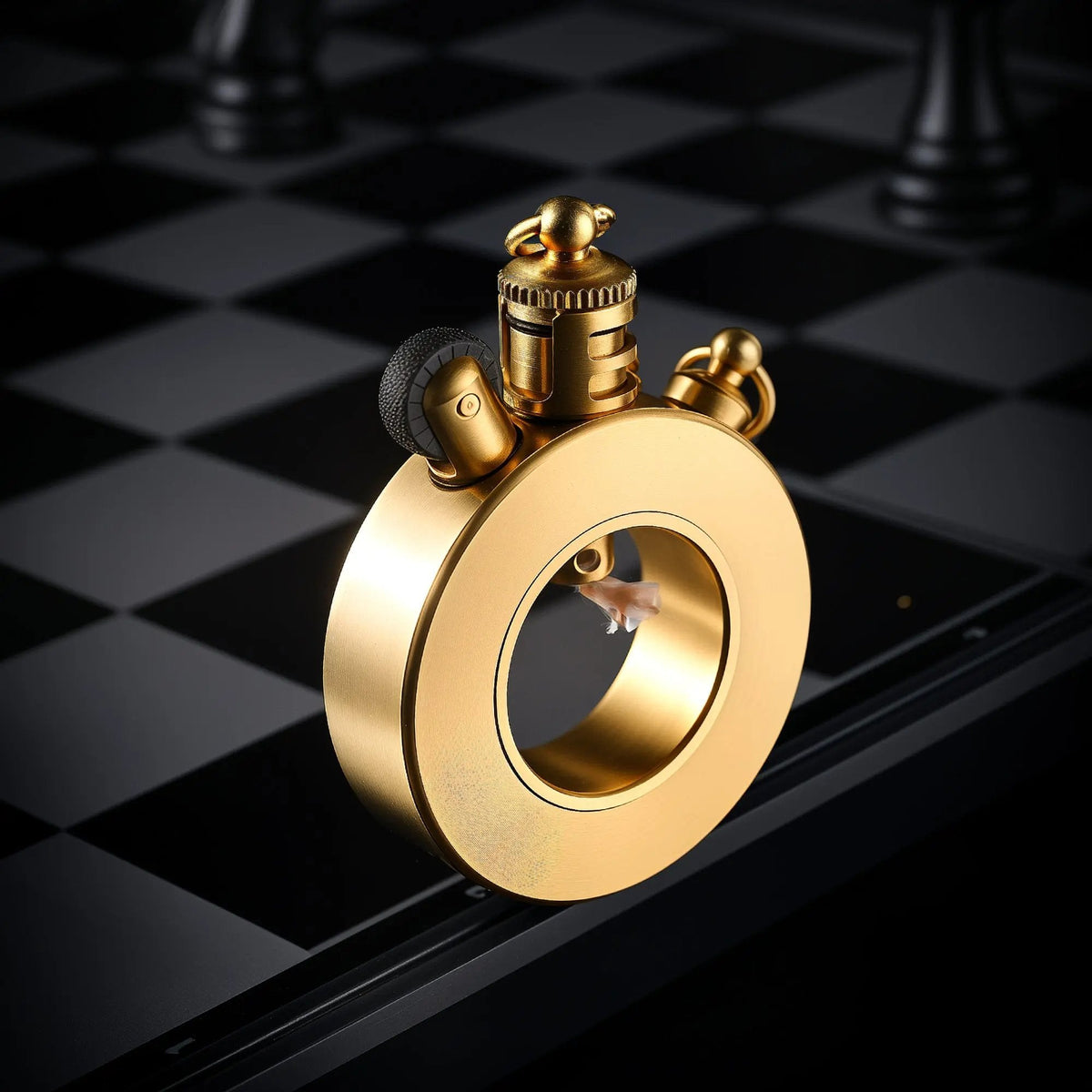 A Thorens Seahorse trench lighter featuring a circular brushed brass body, standing at an angle on a chessboard to highlight its flint wheel and wick placement.