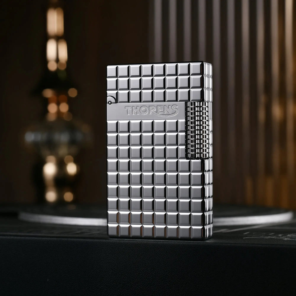 A closed silver Thorens side slip lighter featuring a high-polish argent block pattern, side ignition roller, and engraved Thorens branding.