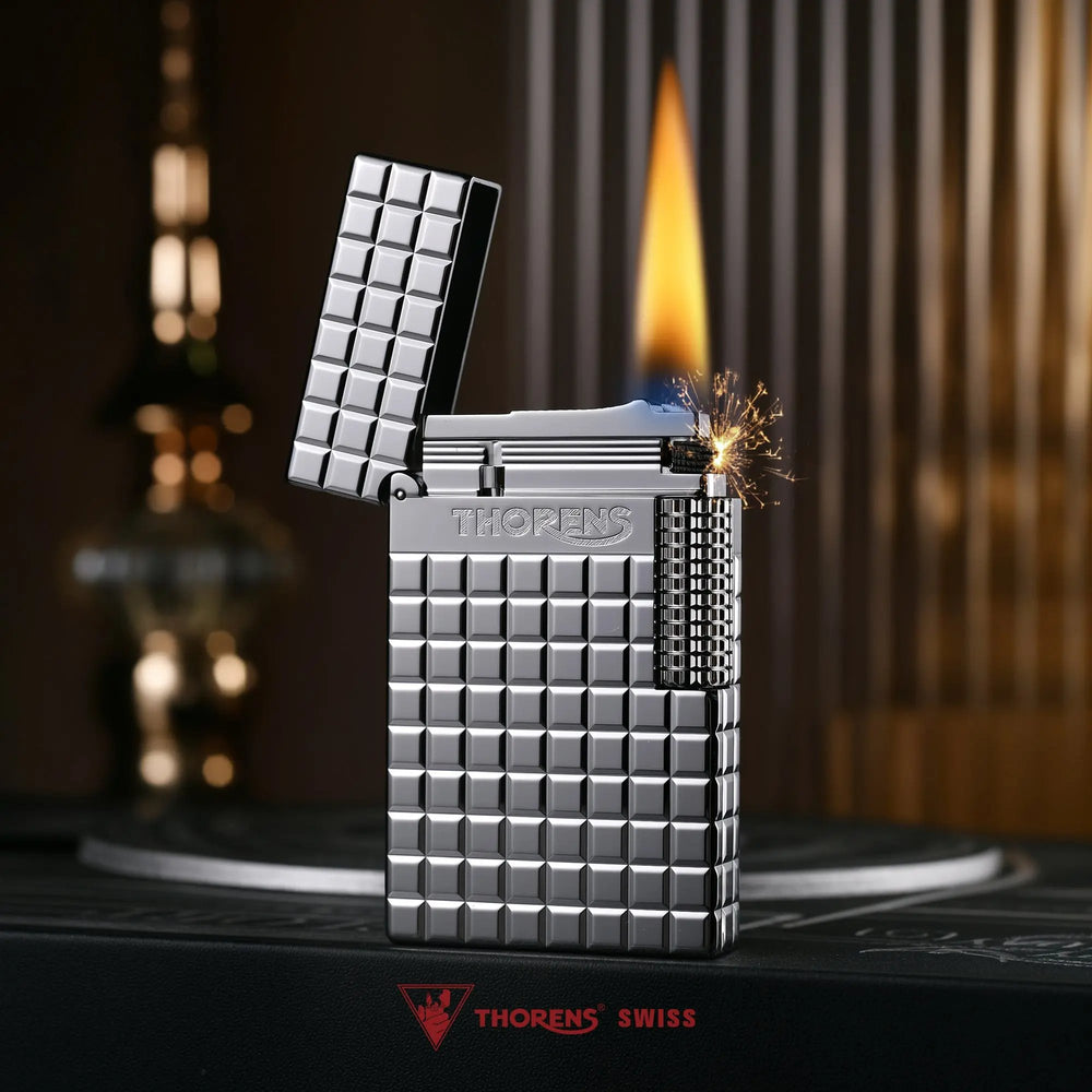 An open silver Thorens side slip lighter with a steady flame, highlighting the polished argent block texture, flint sparks, and side roller mechanism.