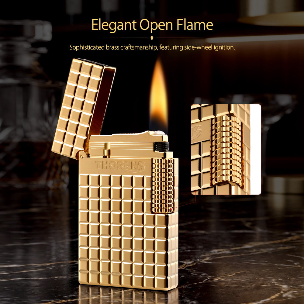 An ignited gold Thorens side slip lighter showing a steady flame and active sparks, highlighting the polished auric block texture and side roller.