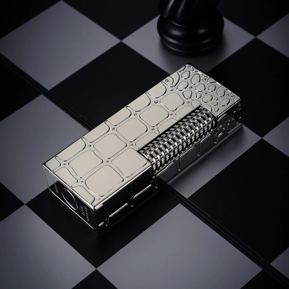 A close-up of a Thorens narrow side slip lighter with a polished silver crocodile skin texture, highlighting the mechanical roller on a chessboard.