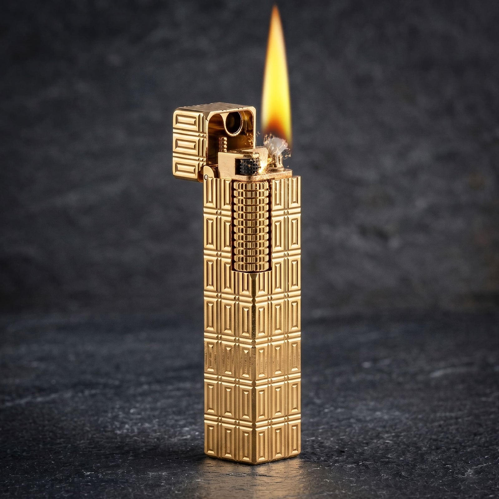 Thorens Side Slip rectangular lighter with geometric block pattern and extended roller in gold finish, igniting with visible flame and spark against a dark textured background.