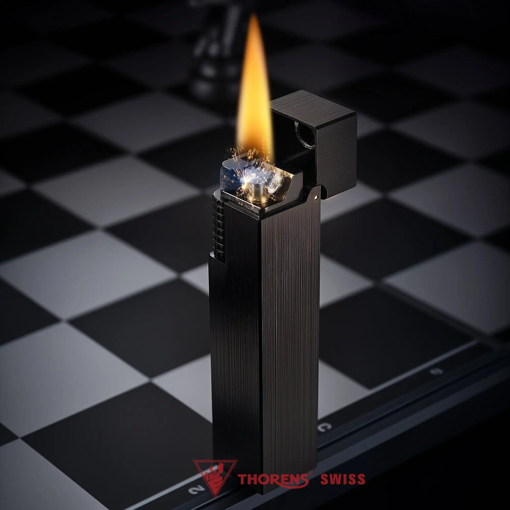A vertical shot of the Side Slip Glossy Black rectangular lighter with its lid open, standing ignited with a flame and sparks on a chessboard.