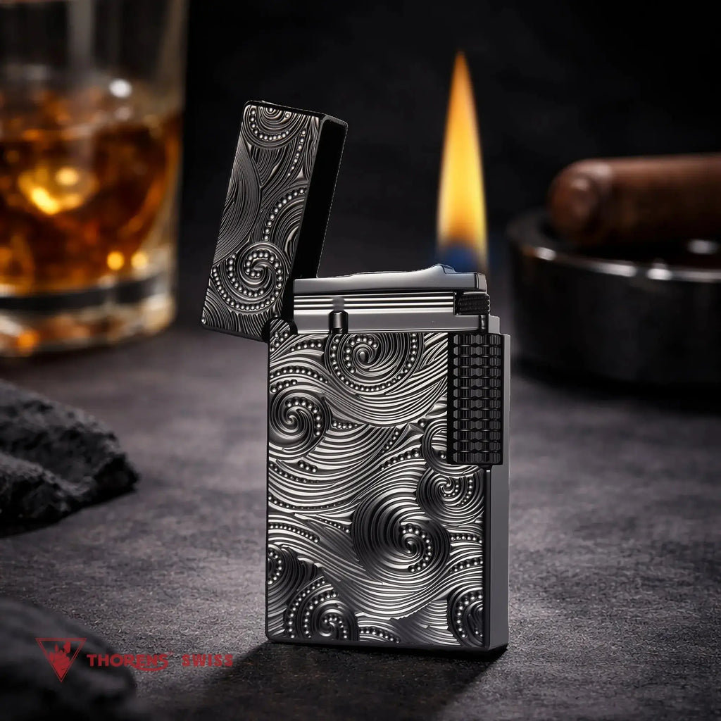 A premium Thorens Side Slip lighter featuring the black Vortex engraved pattern, standing open with a tall, stable flame. The atmospheric background with a glass of scotch and a cigar emphasizes its refined mechanical precision, heritage brass craftsmanship, and sophisticated EDC aesthetic.