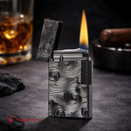 A premium Thorens Side Slip lighter featuring the black Vortex engraved pattern, standing open with a tall, stable flame. The atmospheric background with a glass of scotch and a cigar emphasizes its refined mechanical precision, heritage brass craftsmanship, and sophisticated EDC aesthetic.