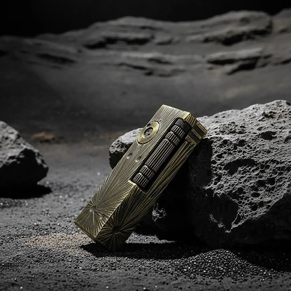 A Thorens Side Slip lighter with a Meteorite Crater textured brass finish resting on volcanic rock, emphasizing its rugged outdoor appeal and mechanical precision.