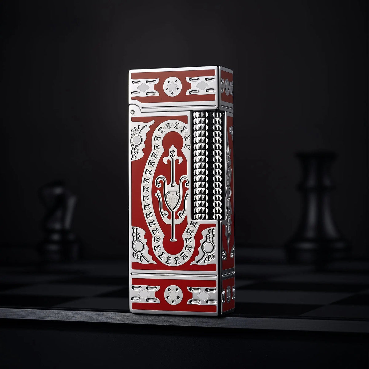 A vertical shot of the Thorens Side Slip narrow lighter in red, showcasing the silver Holy Grail engravings and textured flint wheel against a dark, moody backdrop.