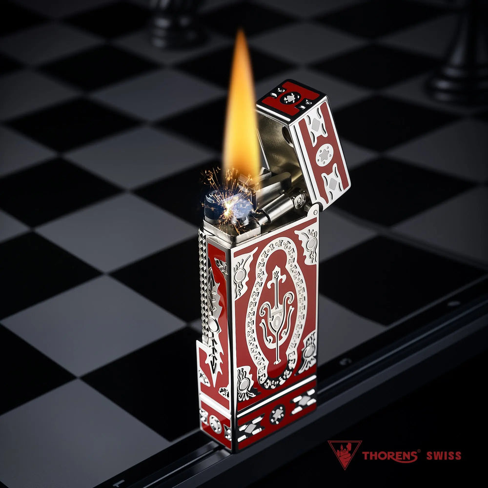 A Thorens Side Slip narrow lighter with the red Holy Grail design, shown ignited with a vibrant flame and mechanical sparks on a chessboard.
