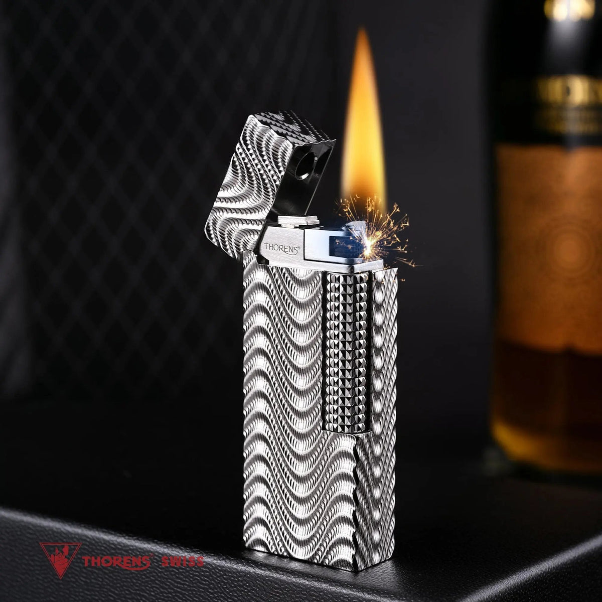 An open Argent Mirage narrow lighter in mid-strike, throwing a burst of sparks and a tall, steady flame that illuminates the high-density silver wave texture against a dark, textured background.