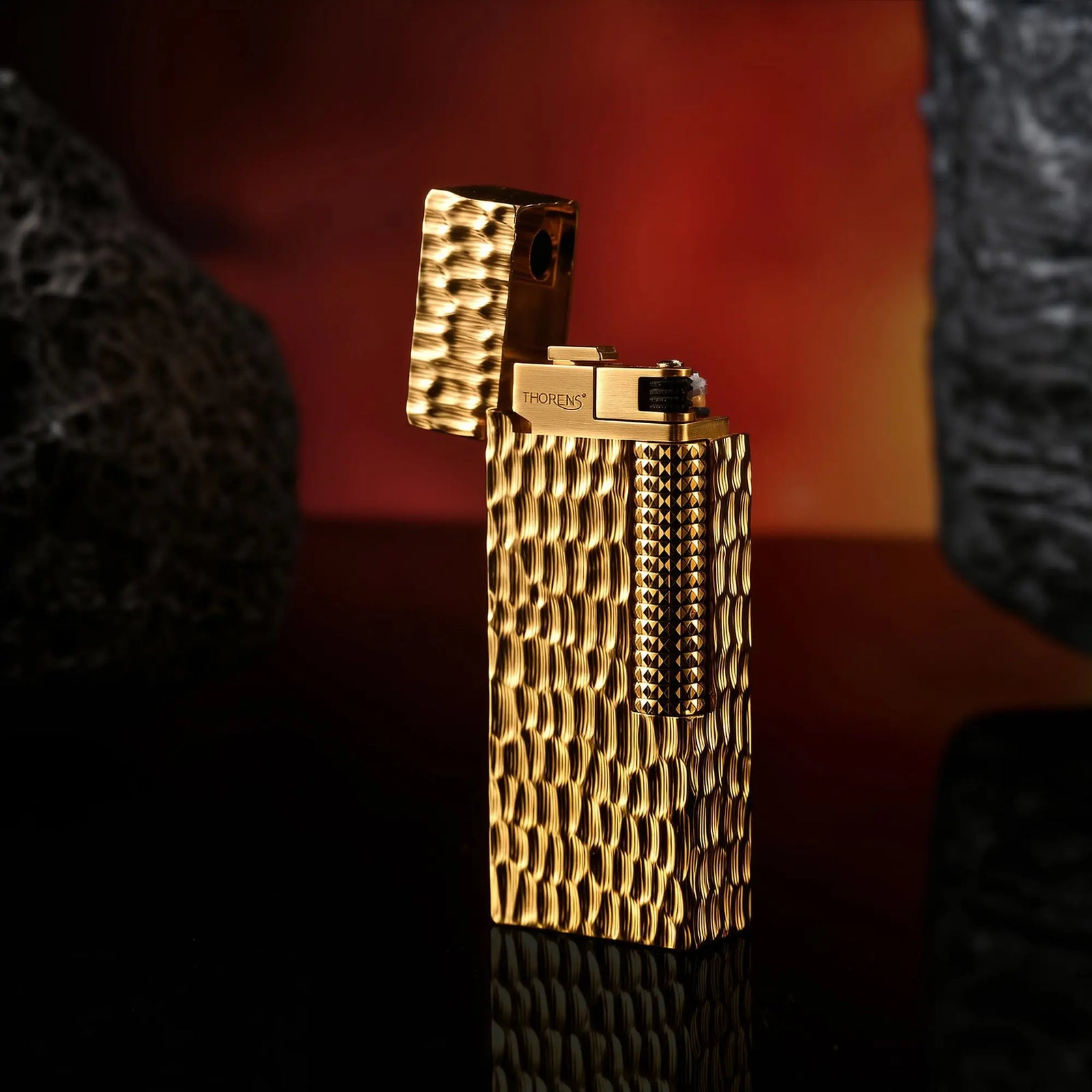 A profile view of the Golden Crater narrow lighter with the lid open, showcasing the hammered brass texture and the precision-engineered ignition head.