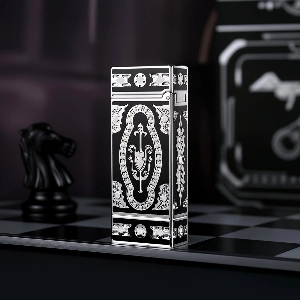 A rear-angle profile of the Holy Grail Black narrow lighter, showcasing the continuous silver baroque engravings along its spine and lid hinge, standing on a monochrome chessboard.