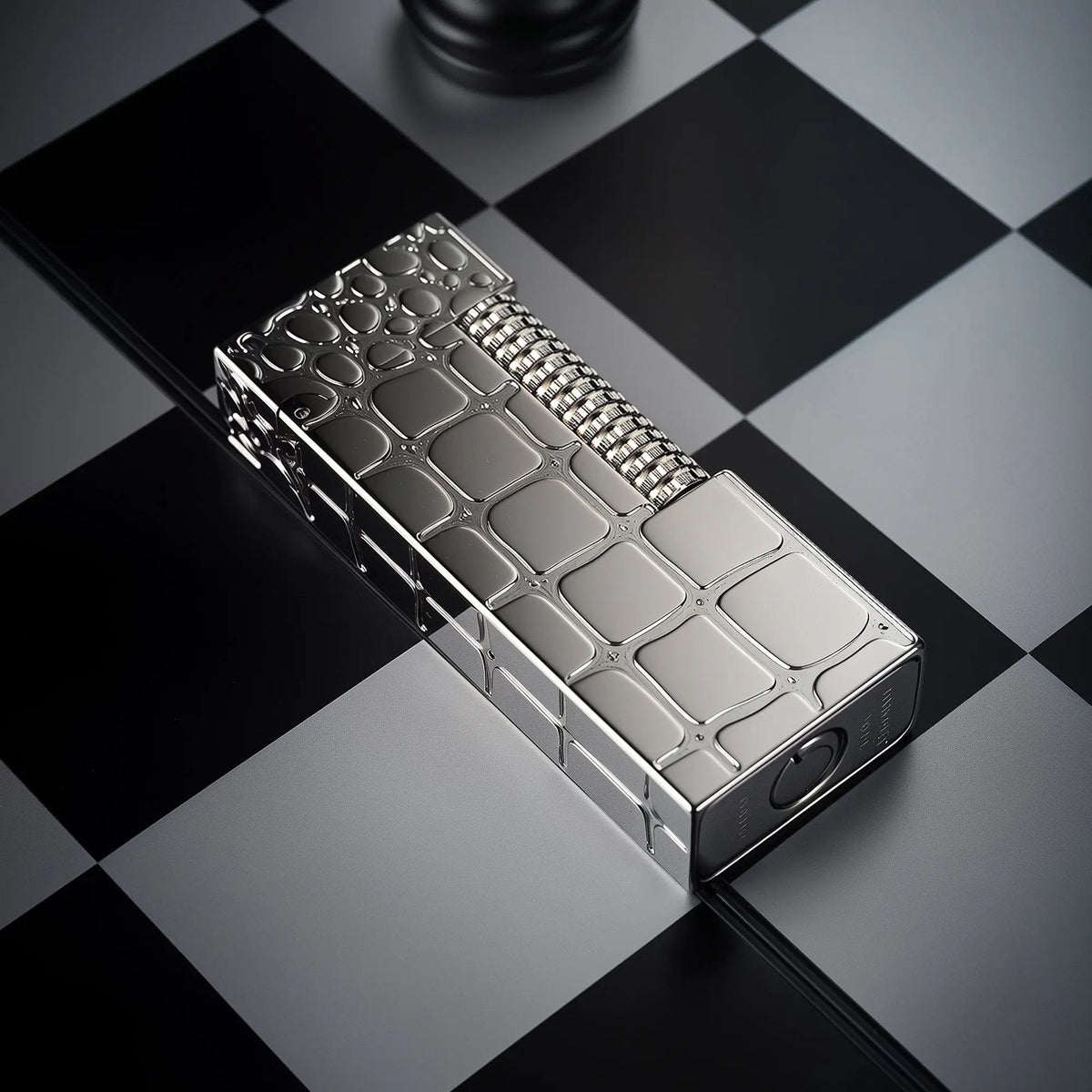 A slim Thorens side slip lighter featuring a polished silver crocodile skin texture, resting on a black and grey chessboard background.