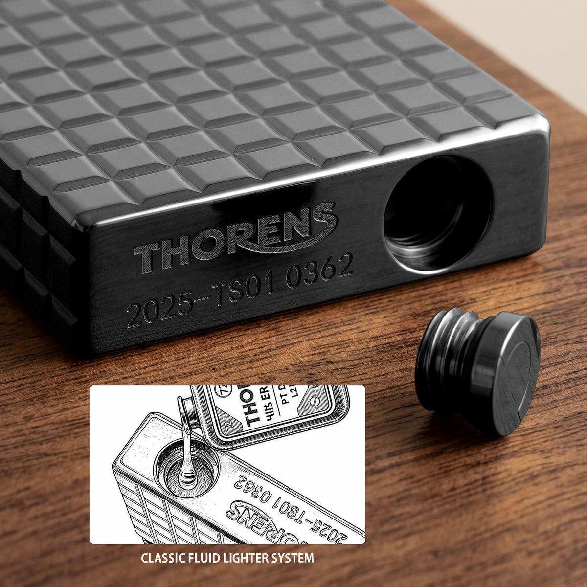 어두운 표면에 기대어 있는 오닉스 블랙 컬러의 토렌스(Thorens) 사이드 슬립 라이터. 매트한 블록 패턴과 측면 롤러 점화 장치, 각인된 로고가 돋보입니다.