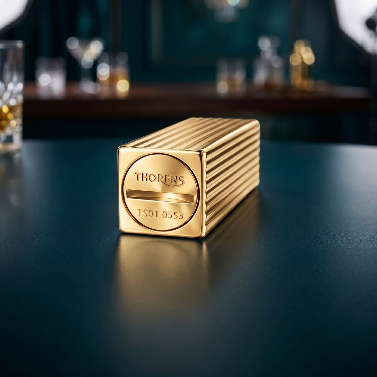 Thorens Side Slip rectangular lighter in gold pinstripe finish showing base engraving with logo and serial detail, placed on a smooth surface.