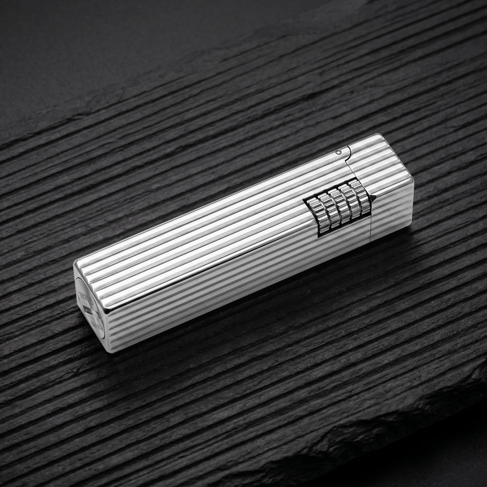 Thorens Side Slip rectangular lighter in silver pinstripe finish resting on a dark wood surface, highlighting linear grooves and integrated side-slide ignition wheel.