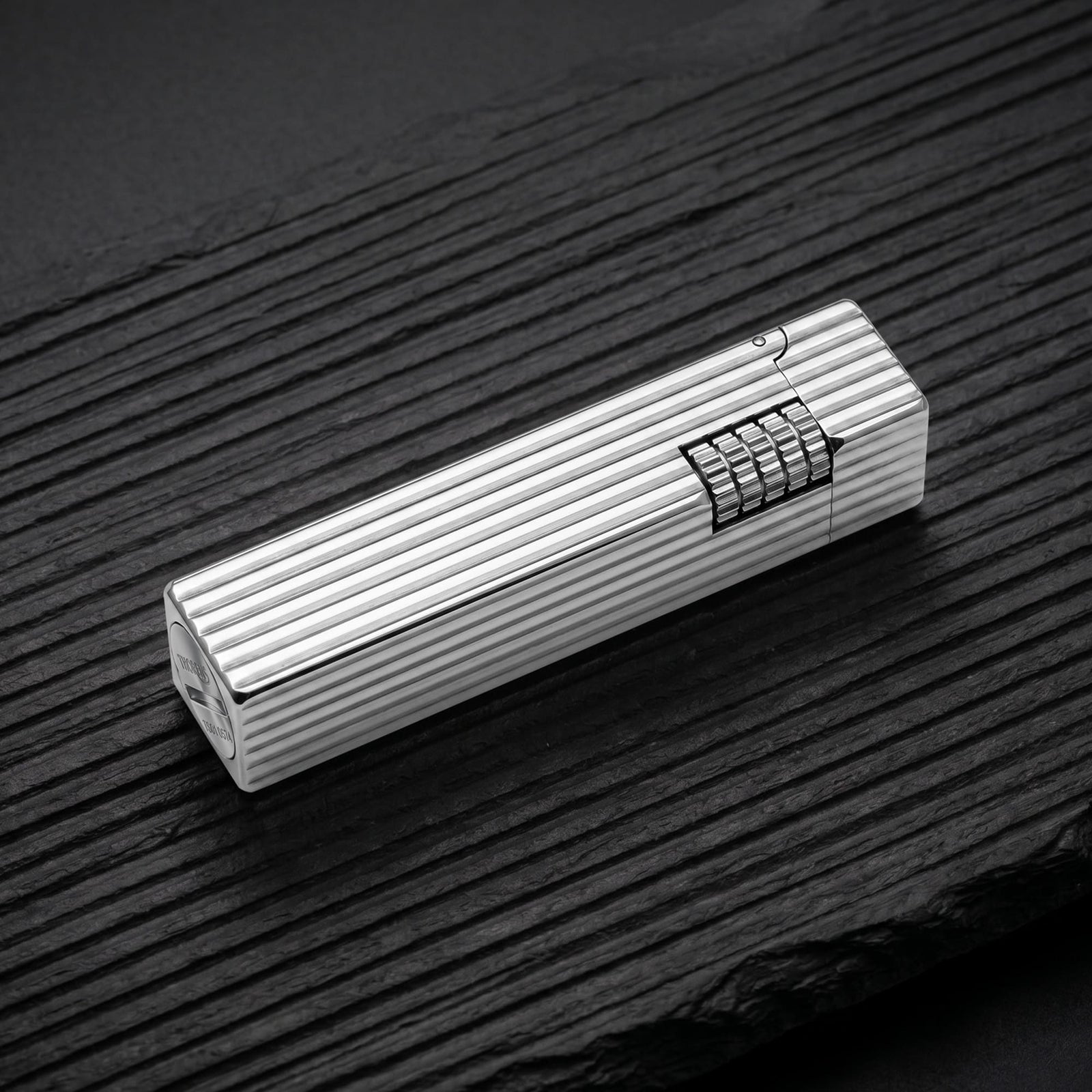 Thorens Side Slip rectangular lighter in silver pinstripe finish resting on a dark wood surface, highlighting linear grooves and integrated side-slide ignition wheel.
