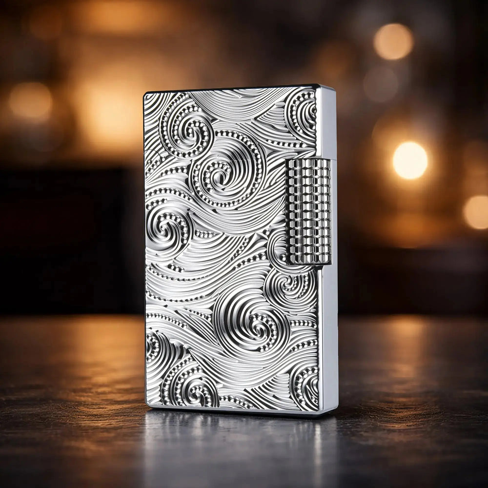 A close-up view of a premium silver Thorens side-slip lighter featuring an intricate, deeply carved vortex pattern on its brass body, showcased on a wooden surface.