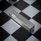 Angled view of a silver small square textured Thorens side-slip rectangular lighter on a black and white checkerboard surface