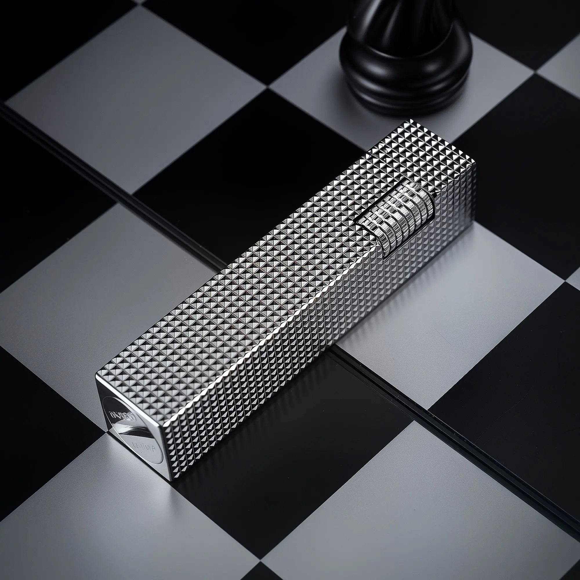 Silver small square textured Thorens side-slip rectangular lighter on a black and white checkerboard surface