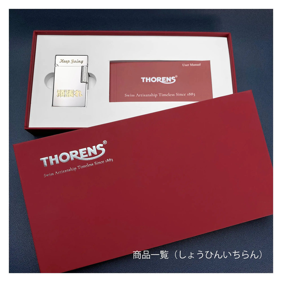"Keep Going" 문구와 일본어 각인이 새겨진 토렌스(Thorens) 기계식 라이터. 스위스의 장인 정신과 전통이 담겨 있으며, 사용 설명서와 함께 고급스러운 레드 기프트 박스에 담겨 있습니다.