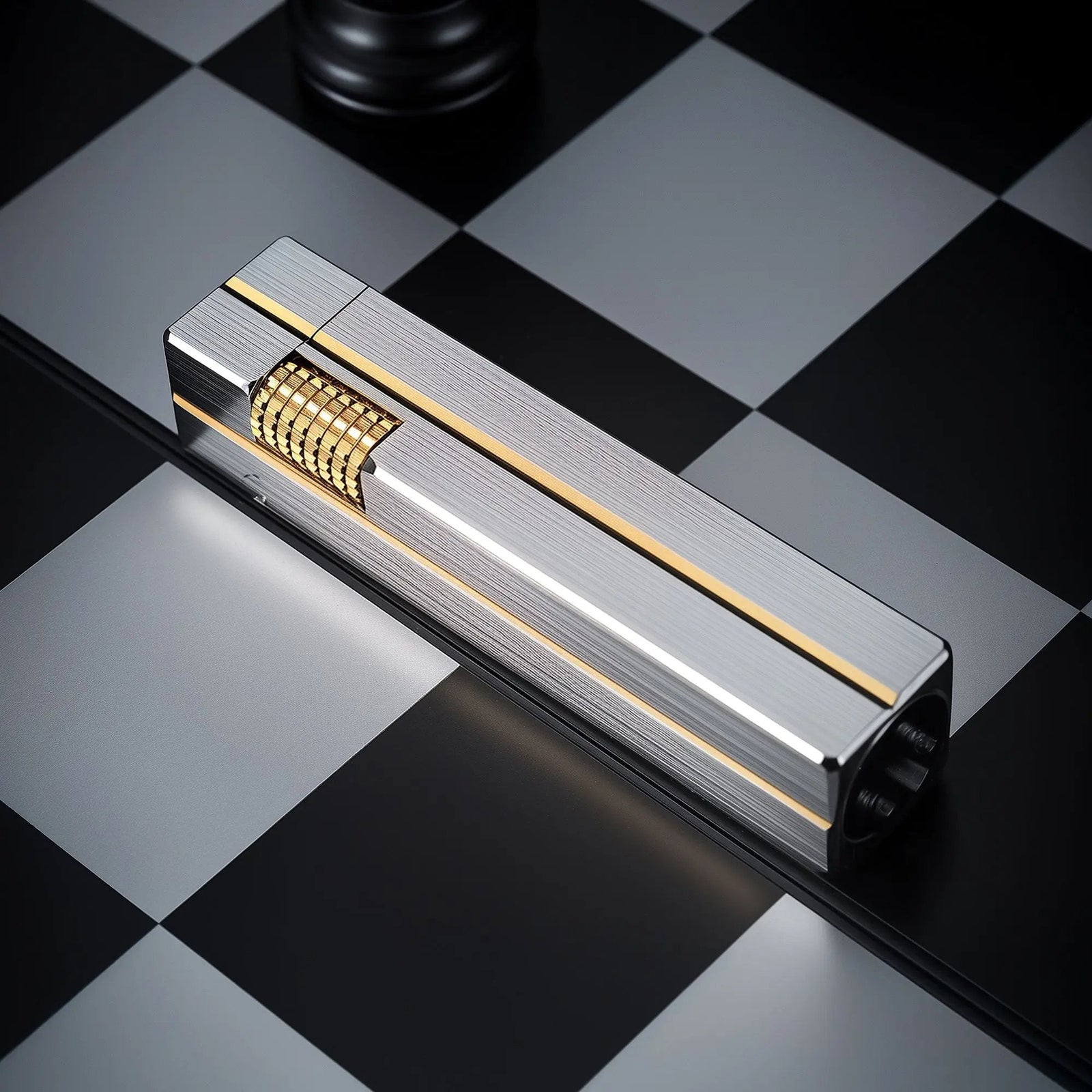A textured metallic Side Slip Rectangular Lighter, with gold accents and ignition roller, sits on a black and white checkerboard surface.