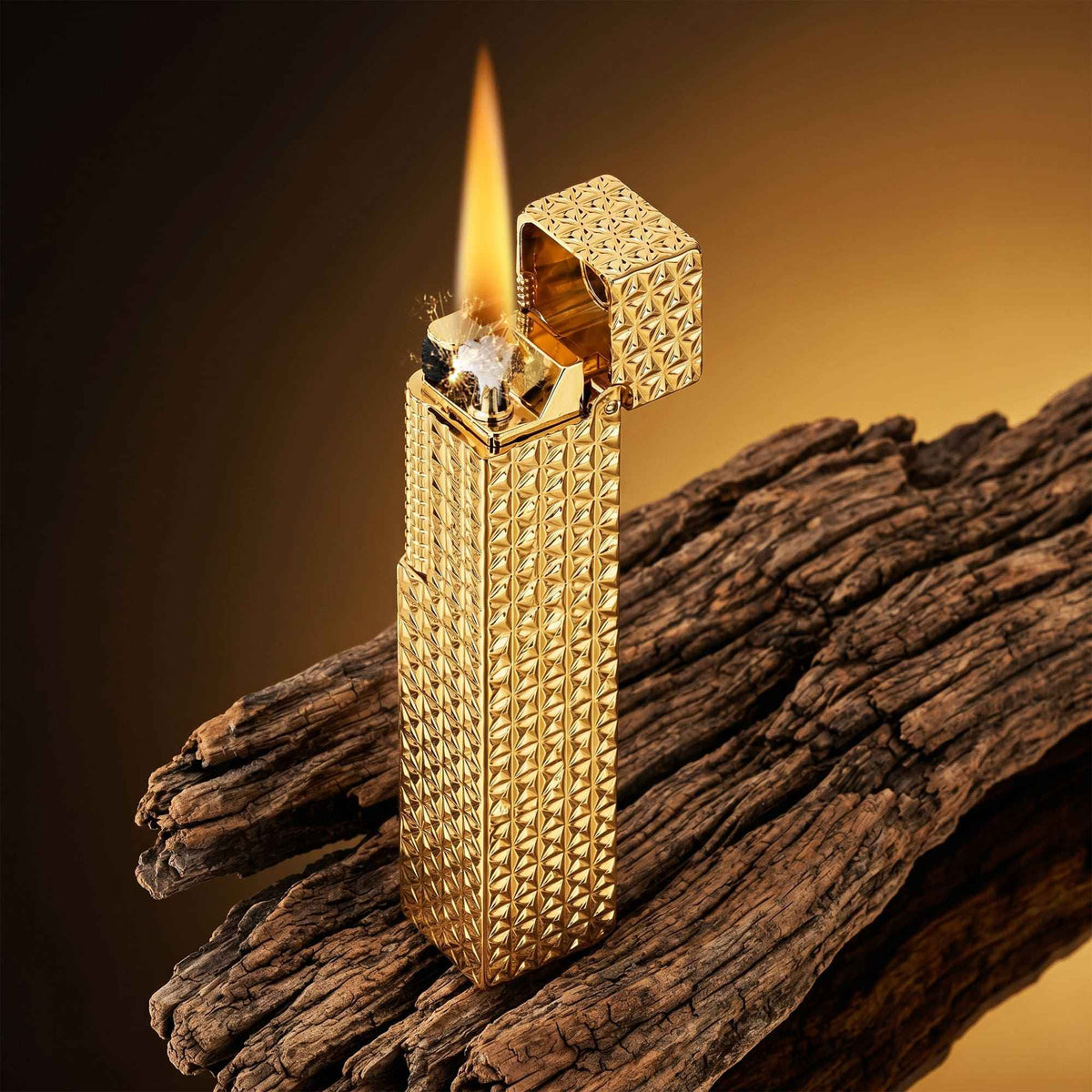 Thorens rectangular lighter with gold starburst pattern and extended roller shown ignited on textured wood, lid open with visible spark and flame.