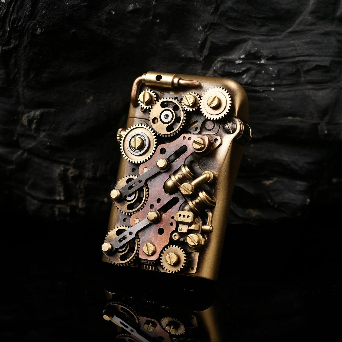 A Thorens Steampunk-Twin Torque bottom-fill lighter showcasing complex brass gears and mechanical linkages against a textured dark stone backdrop.