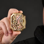 Thorens Steampunk Matchbox Twin Torque lighter held in hand, showing exposed brass gears, copper plates, and intricate mechanical components.