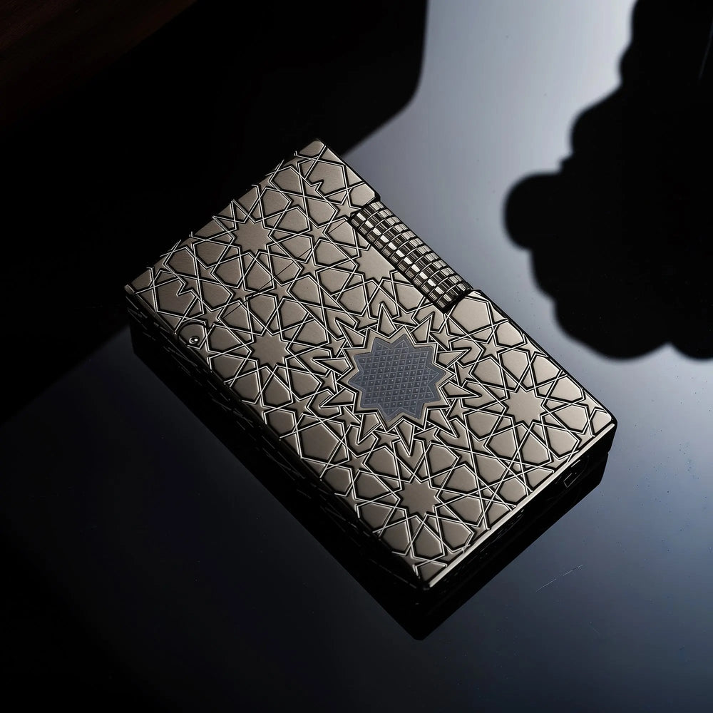 A top-down view of the Thorens Stellar Mesh Black lighter on a reflective black surface, showcasing the precise geometric star-mesh engraving and tactical black finish.