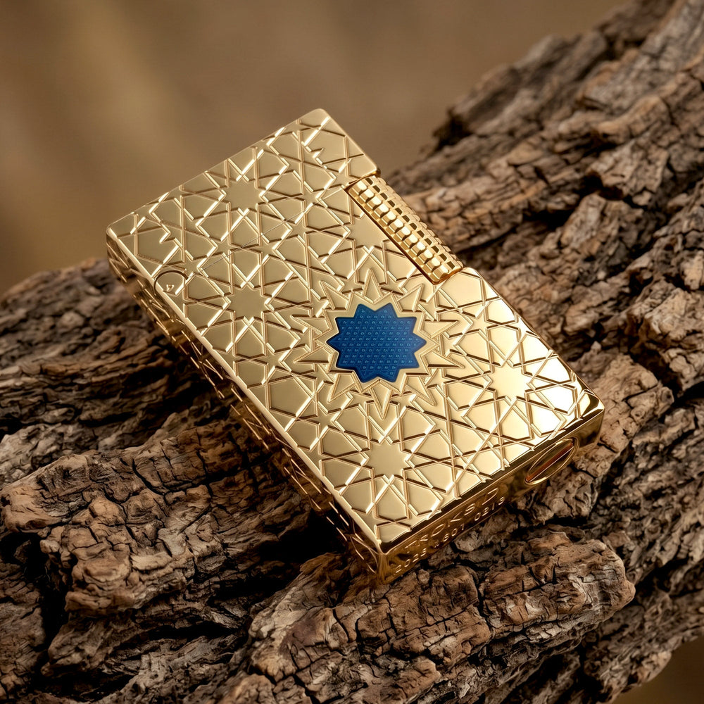 A Thorens Stellar Mesh Gold lighter featuring an intricate geometric star engraving and a central blue mesh inlay, resting on a polished wood surface next to a vintage pedestal.