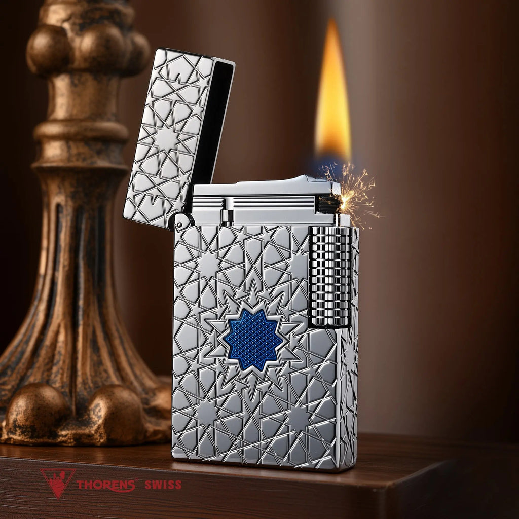 A Thorens Stellar Mesh Silver lighter with an open lid, captured at the moment of ignition to show the flint spark and flame against the intricate silver geometric star pattern and blue mesh center.
