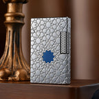 A Thorens Stellar Mesh Silver lighter featuring an intricate geometric star engraving and a central blue mesh inlay, resting on a polished wood surface next to a vintage pedestal.