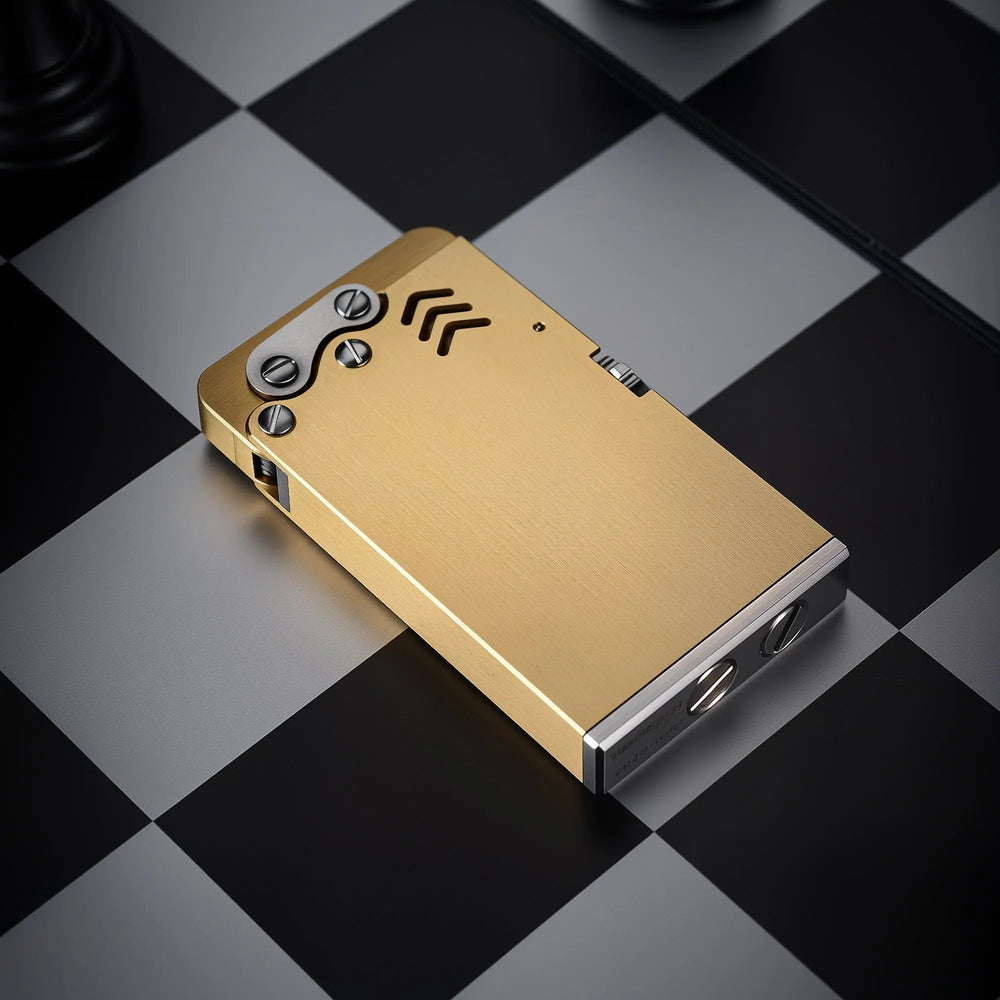 Brushed brass Thorens Thin Ejection lighter with industrial screw details, lying on a black and white checkered chessboard background.