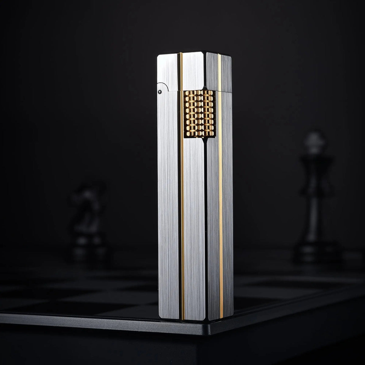 A vertical shot of the Side Slip Star Shine rectangular lighter featuring a brushed silver body and gold inlay, standing on a dark chessboard.