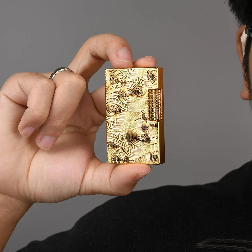 A person holding a Thorens gold vortex engraved lighter, demonstrating its compact size and ergonomic design for comfortable everyday carry.